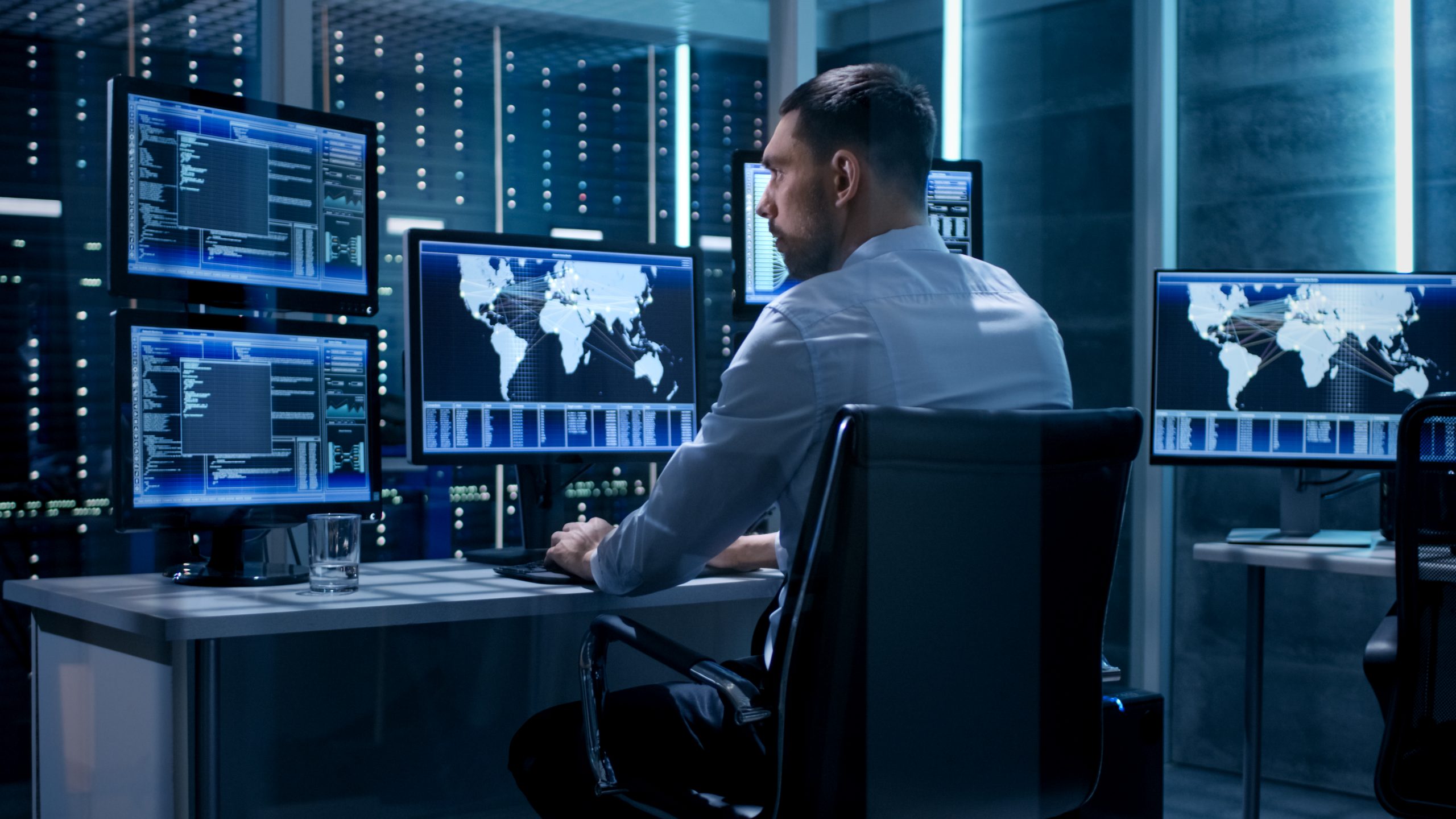 Technical Controller Working at His Workstation with Multiple Displays. Displays Show Various Technical Information. He’s Alone in System Control Center.