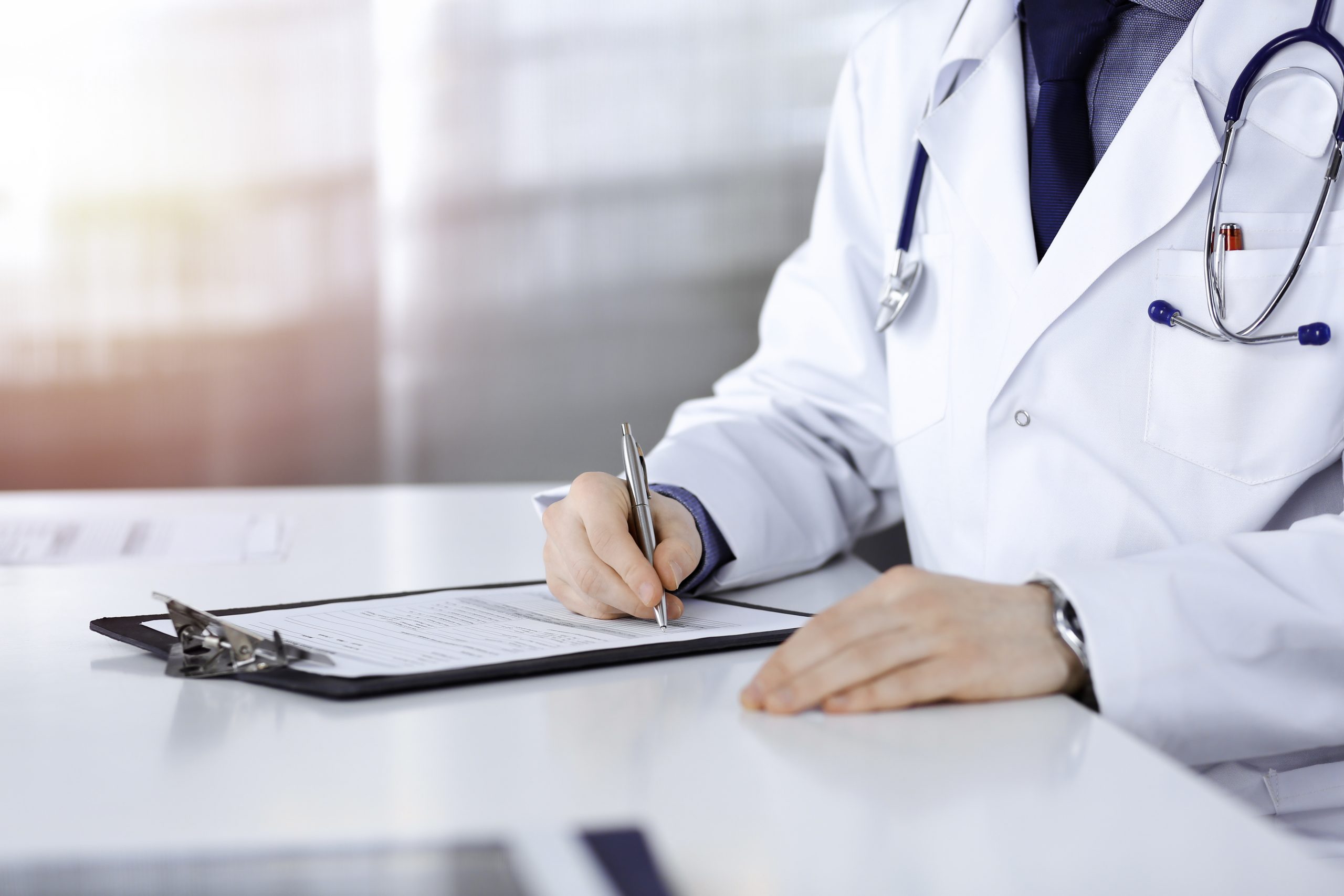 Unknown,Male,Doctor,Sitting,And,Working,With,Clipboard,Of,Medication